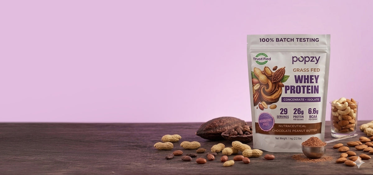 Popzy whey protein package with chocolate and nuts on a wooden surface against a pink background